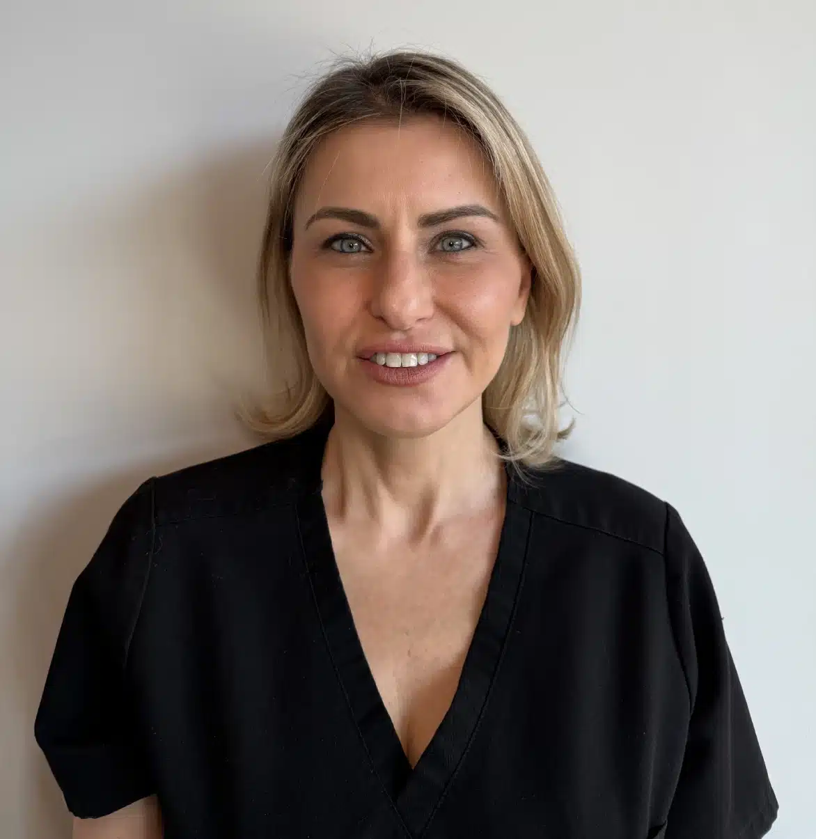Photo of Floria from Liv Aesthetics LLC, wearing a black top and smiling gently. She is posed against a clean, softly lit background, reflecting a calm and professional demeanor.