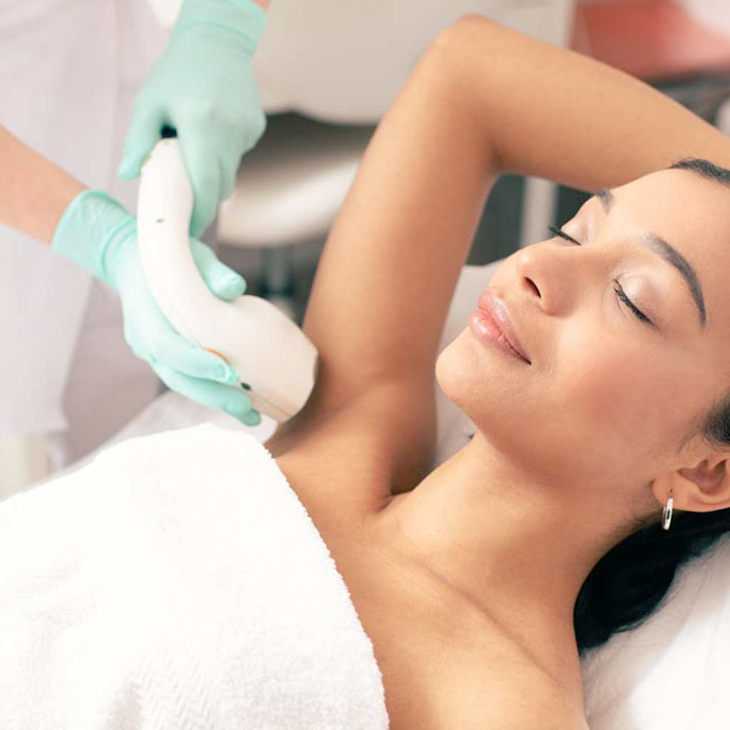 Smiling woman undergoing laser hair removal on her armpit